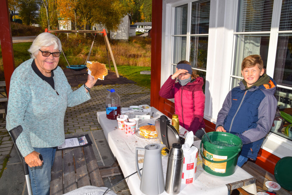 VAFLER: Eivind Førsund Kile (fra høyre) og Rebecca Olsen solgte vafler i flere timer utenfor Joker i Mykland. En av kundene var Frøydis Kile, som her nettopp har fått en fersk vaffel. FOTO: RAYMOND ANDRE MARTINSEN