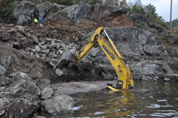 Gravemaskin i vannet ved Frolands Verk