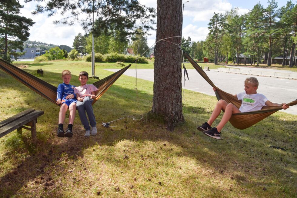 HENGEKØYE: Utenfor Nidarhall var det plassert ut flere hengekøyer mellom trærne. Tobias, Vicotr og Emil synes det var moro å slappe av i disse og leke med dem i sommervarmen. FOTO: RAYMOND ANDRE MARTINSEN