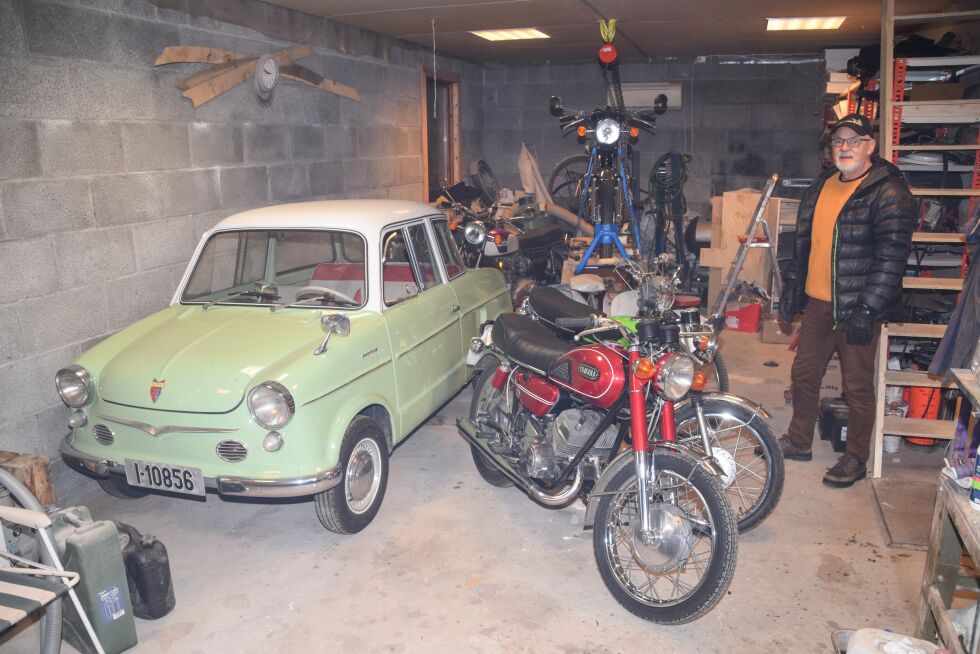 KJØRETØY: Kjell Rasmussen med noen av de mange kjøretøyene sine i garasjen hjemme på Messel. Gjennom flere år har han restaurert opp både biler og motorsykler. FOTO: RAYMOND ANDRE MARTINSEN